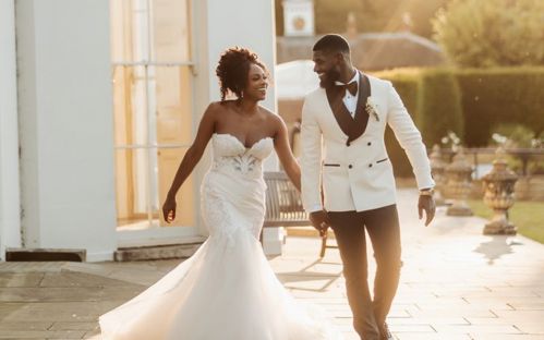 Rochelle and Andrew walking along the back of Hylands House at dusk holding hands.