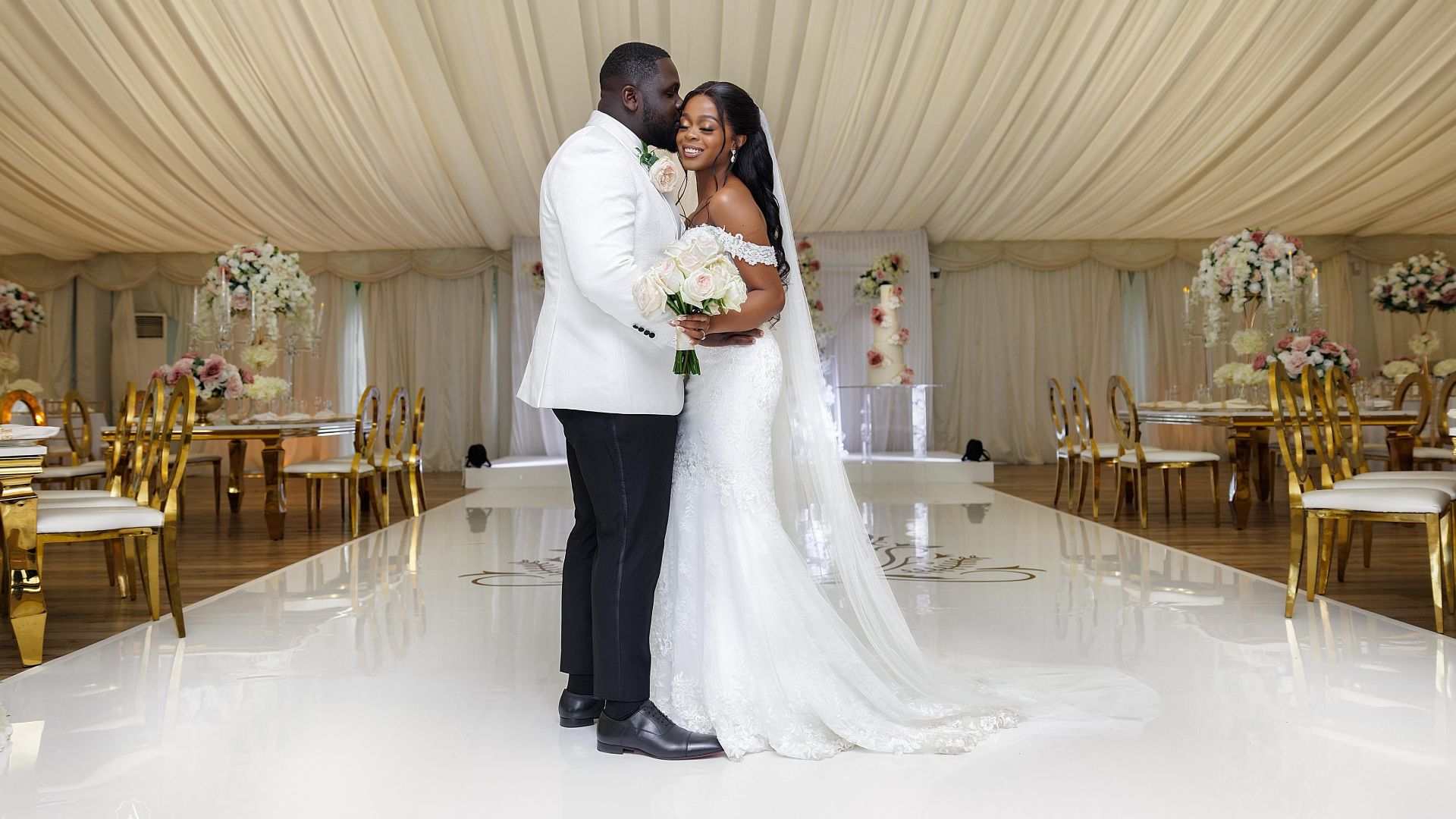 A groom kisses the forehead of his bride on the dancefloor of their reception. 