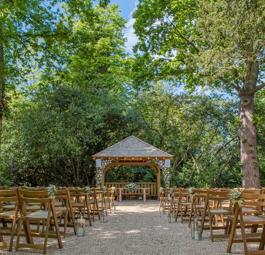 The gazebo of the Outdoor Ceremony Garden decorated with pink and white flowers. 