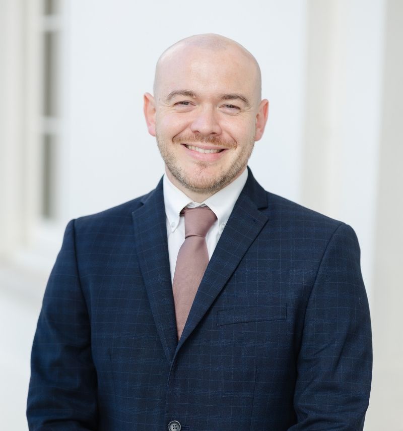 Tom, a man wearing a navy suit and blush-coloured tie.