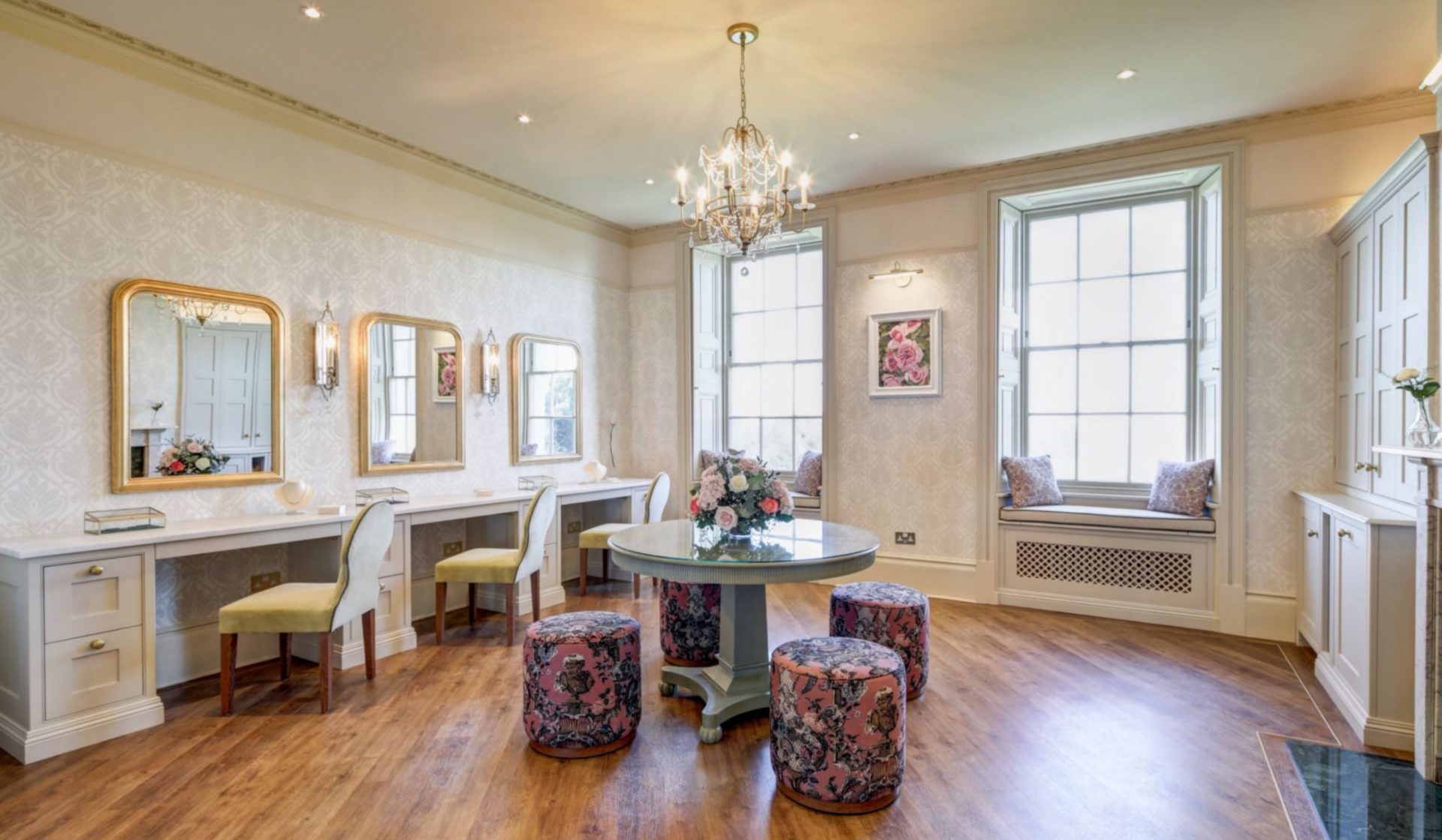 The Rose Room of the Wedding Suite featuring a table with chairs around it and multiple makeup stations. 