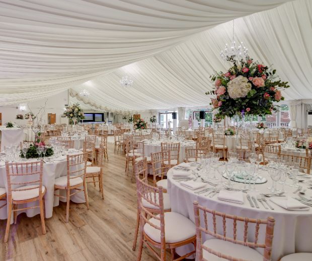 The Grand Pavilion set for a wedding reception with round tables and pink and white bouquets. 