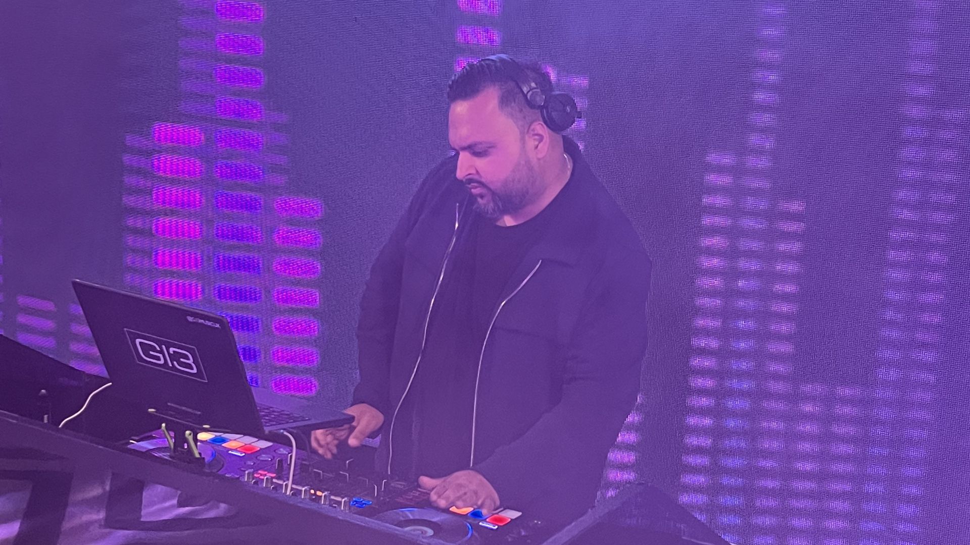 Gurdeep from G13 Music wearing headphones and using his DJ deck. 