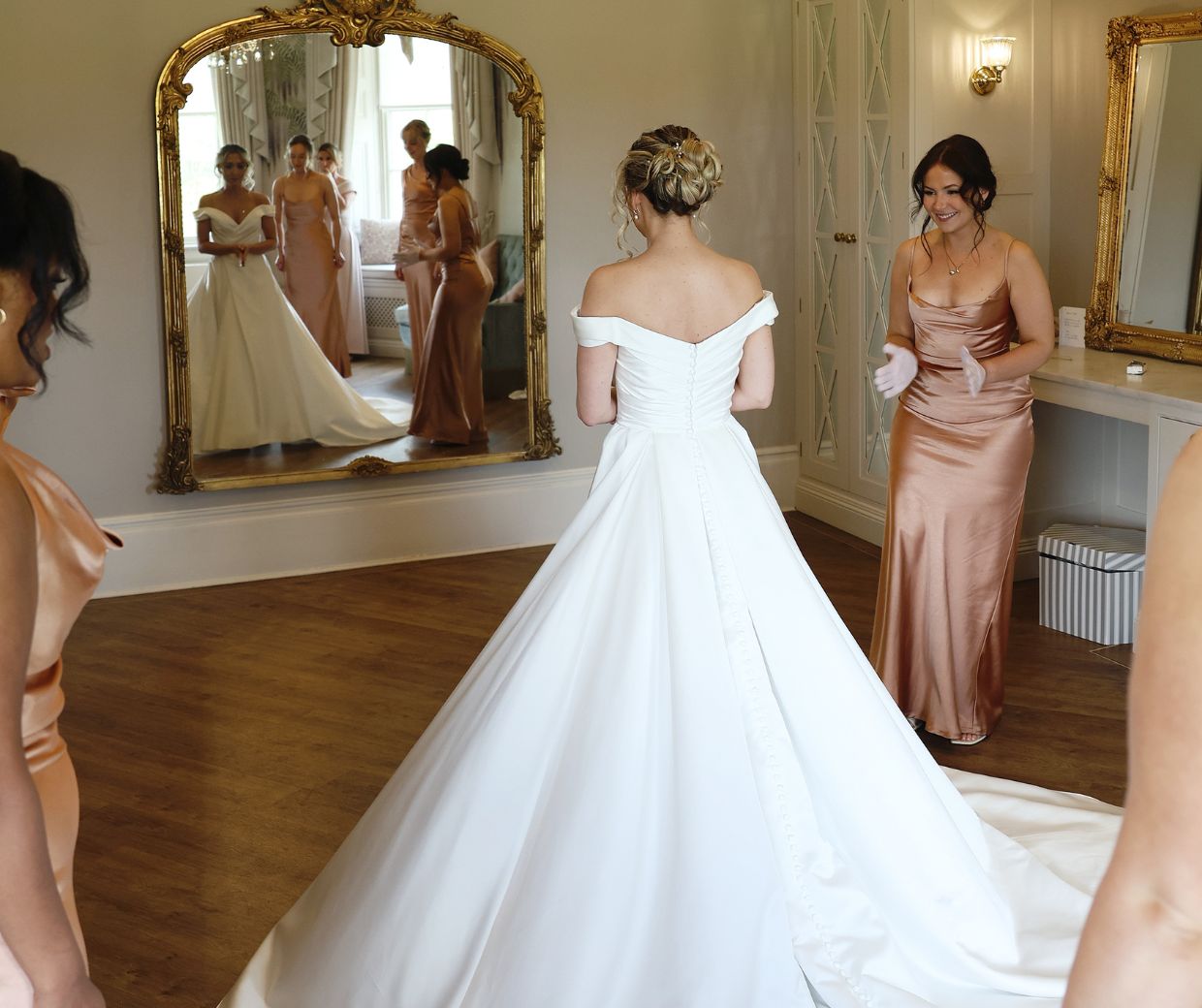 A bride looking in the mirror surrounded by her wedding party. 