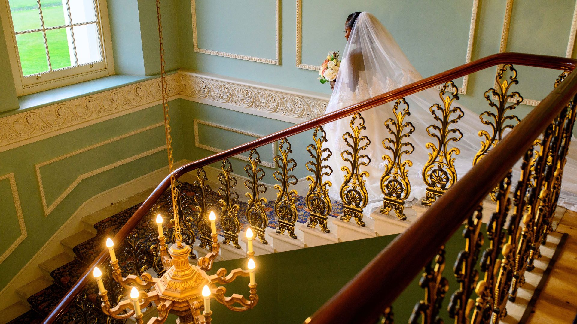 A beautful bride walks down the grand staircase in Hylands House