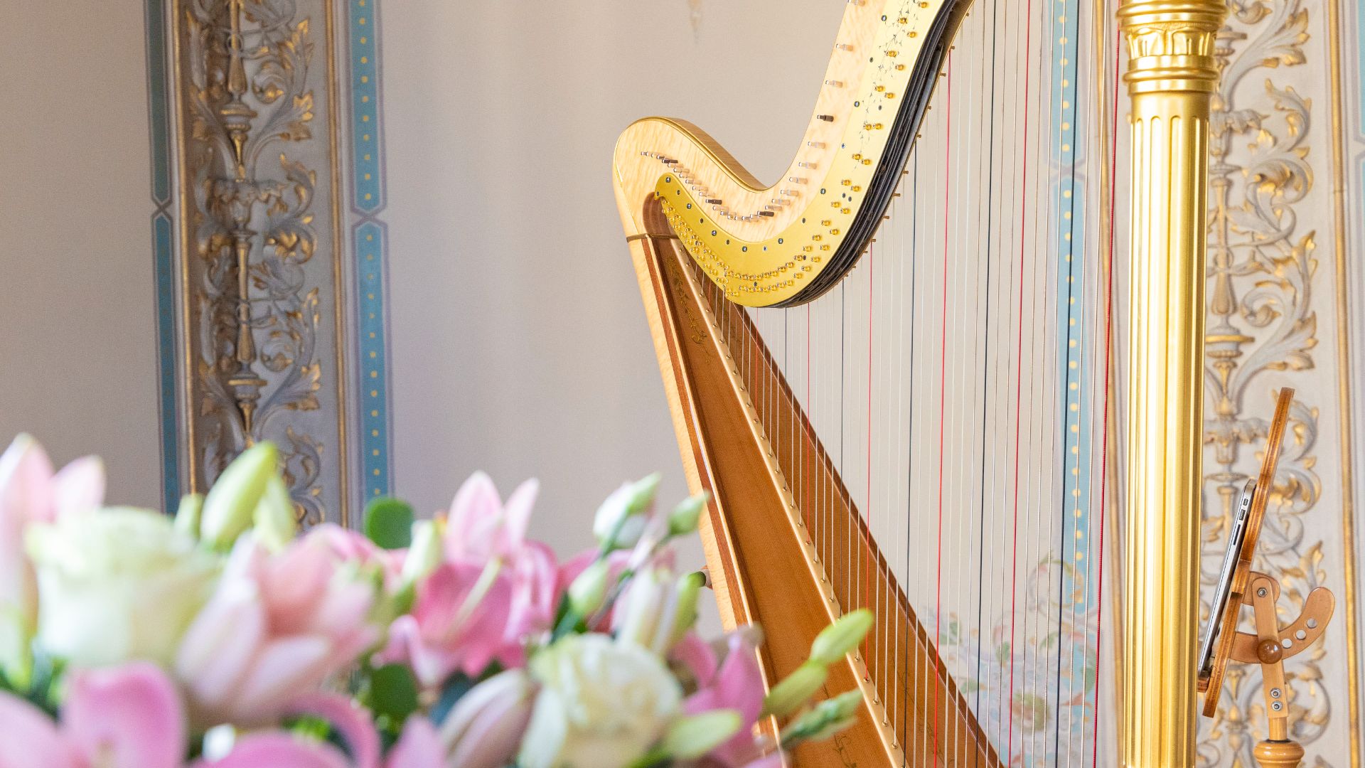 A gold harp in the Drawing Room with pink and white flowers in the foreground